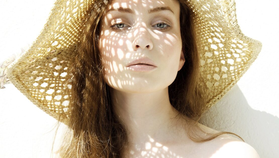 Mulher branca com chapéu trançado com filtro solar durante o verão